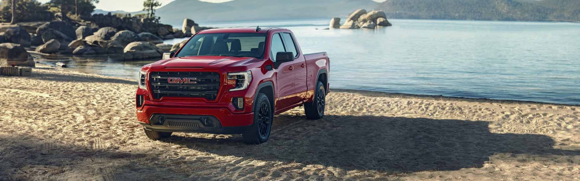 A GMC Sierra 1500 parked at the edge of a serene lake, surrounded by nature.