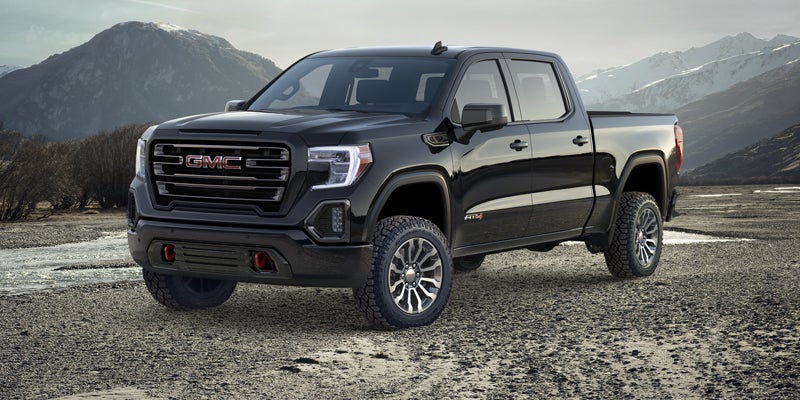 A black GMC Sierra 1500 parked in front of a mountain range.