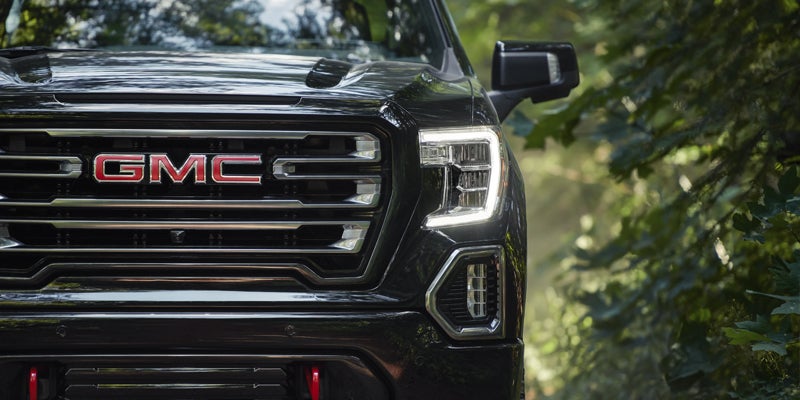 A close front view of a GMC Sierra 1500, with trees visible in the background.
