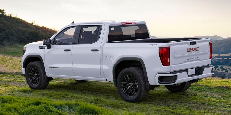 white GMC Sierra 1500 in side profile, parked on a green mountain.